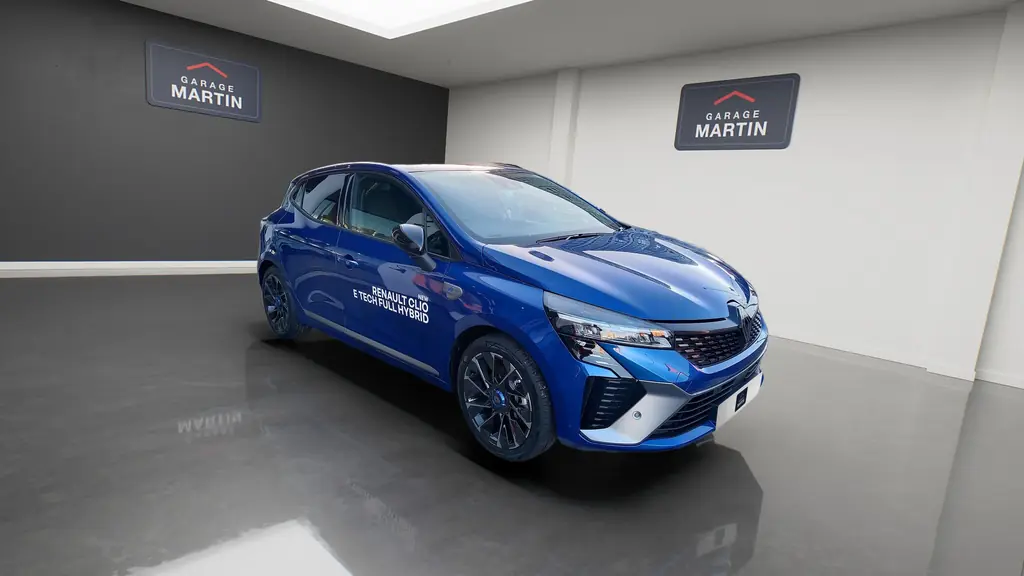 Une Clio bleue dans le studio, le logo du Garage Martin au mur et sur sa plaque
